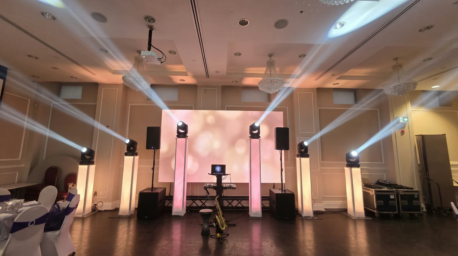 The same six-totem rig with a wide LED video wall standing behind the DJ booth